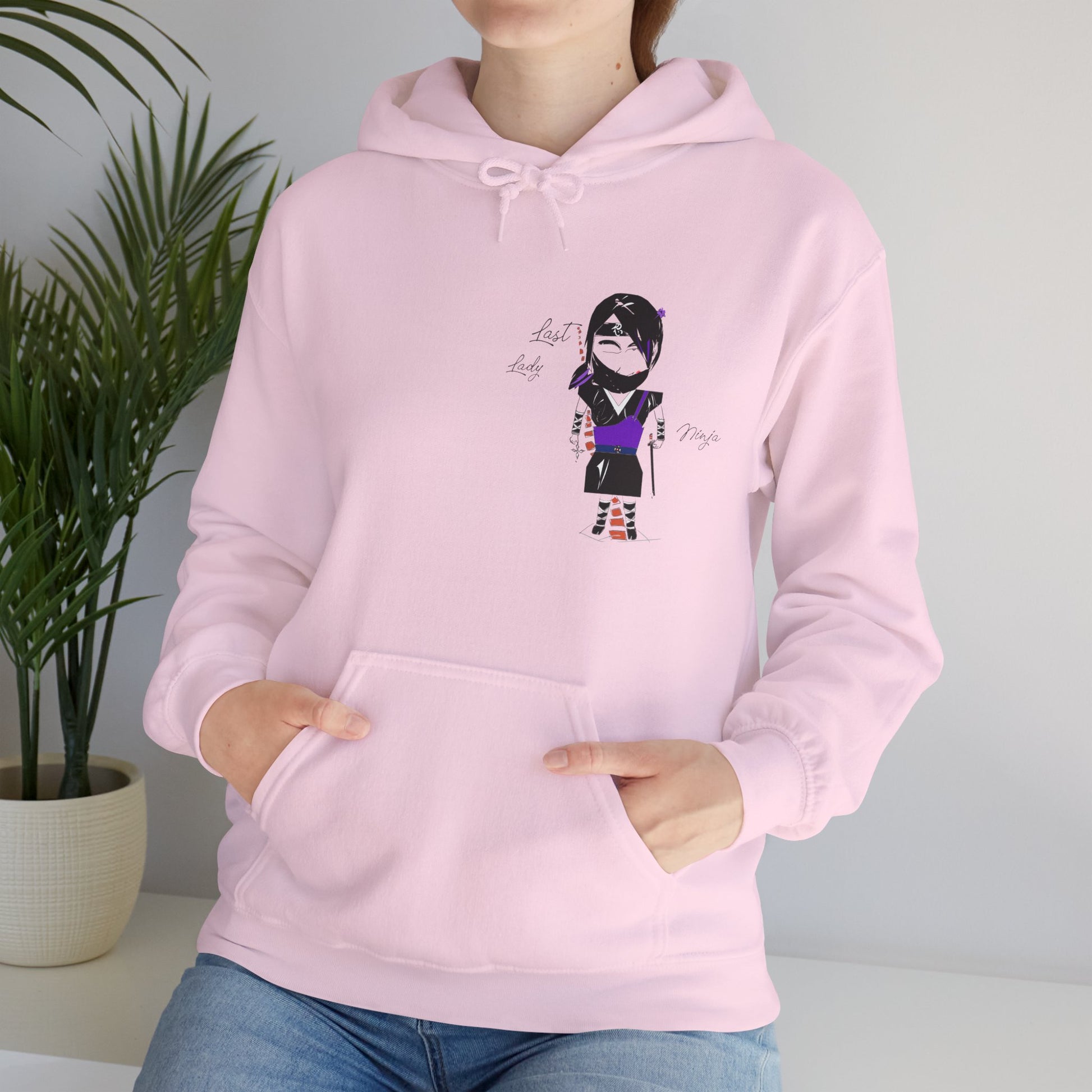 A lady model wearing a pink hoodie with a lady ninja graphic design on a neutral background