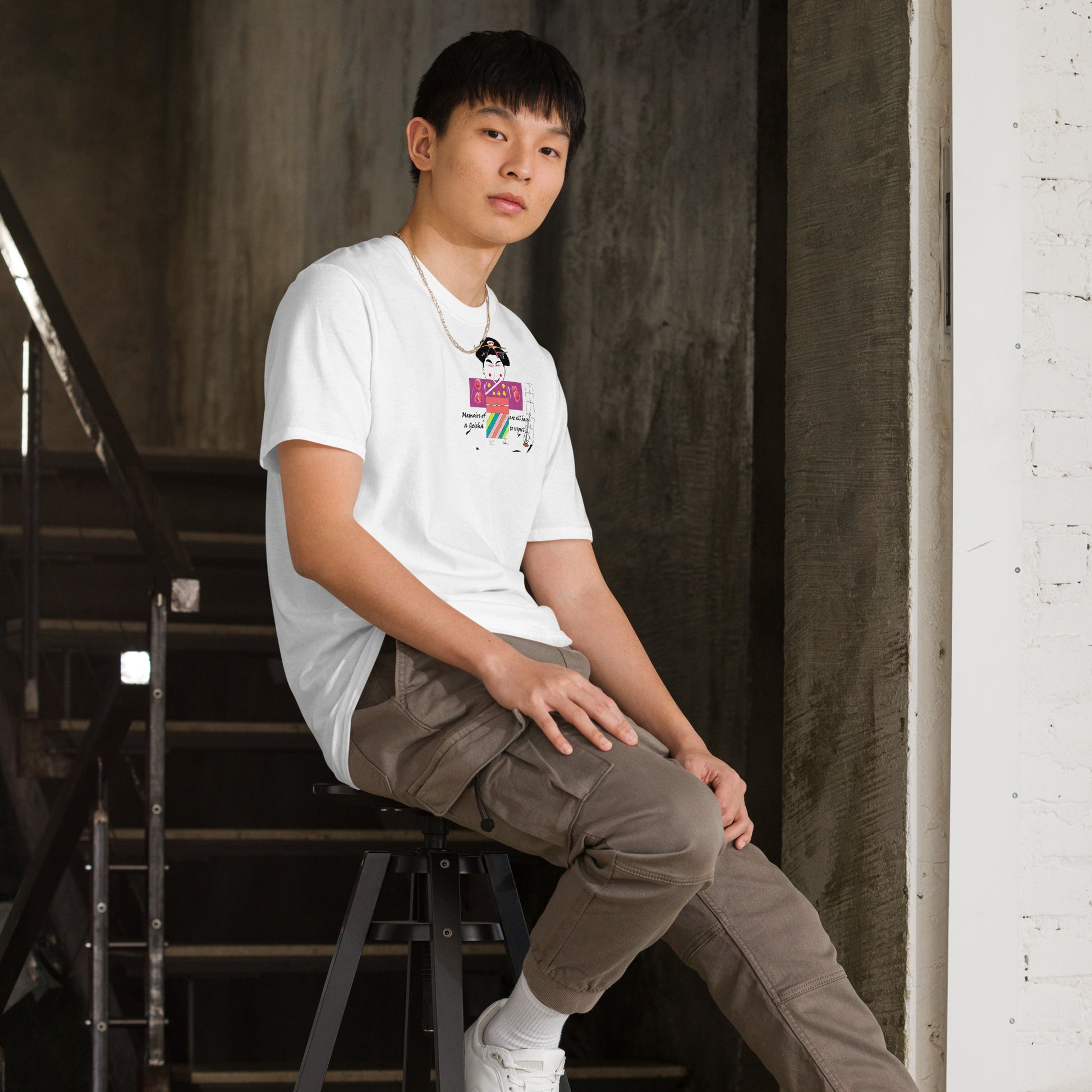 Right side view of an Asian man model wearing a white t-shirt with a Japanese Geisha graphic design sitting on stairs on a dark background