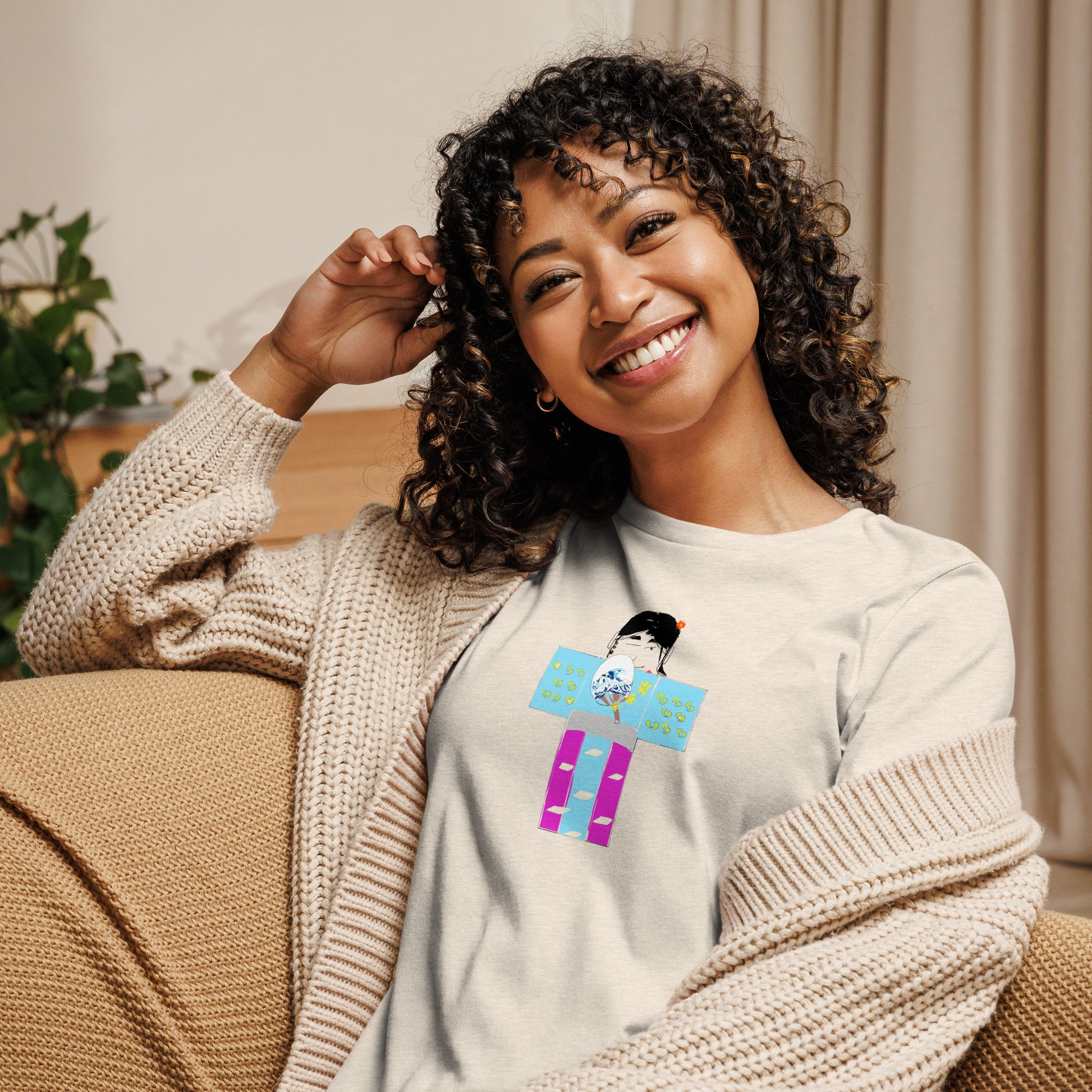 Front view of a woman model wearing a beige t-shirt with a yukata girl graphic design sitting in a couch