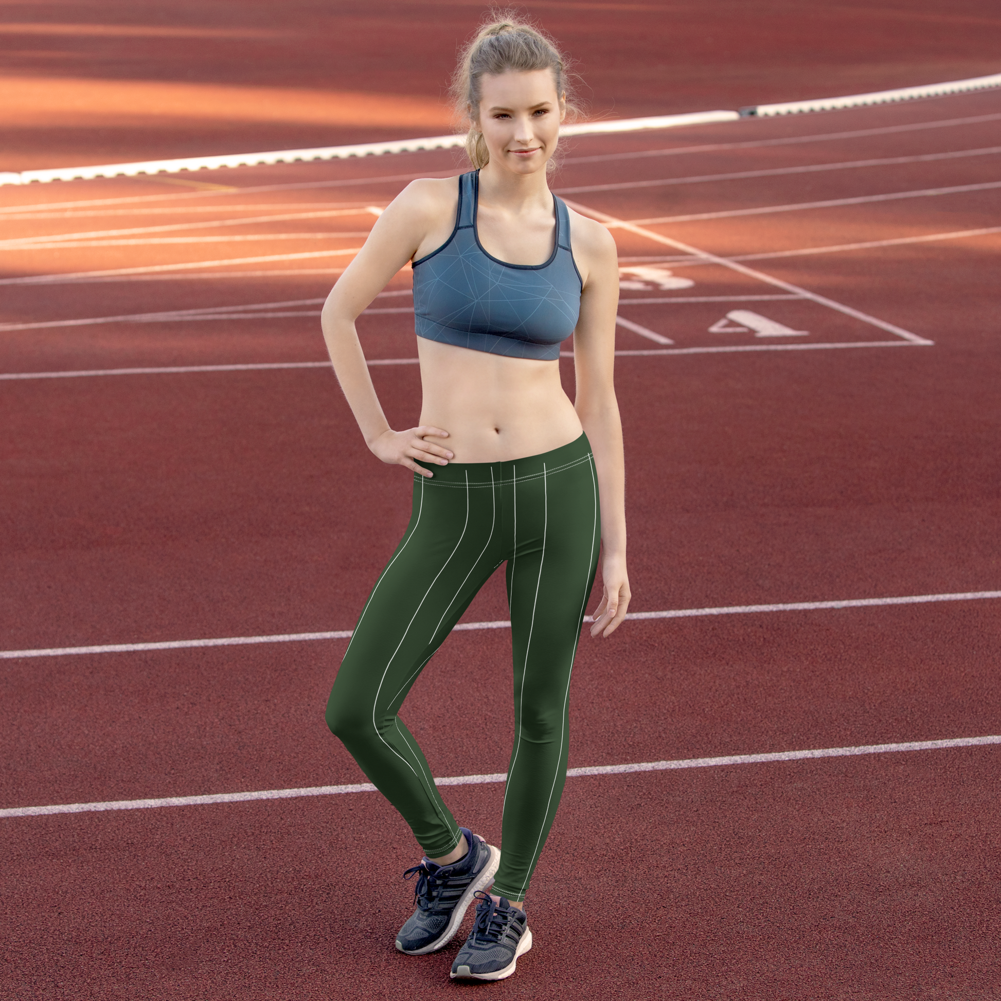 Woman in athletic wear and leggings standing on a running track