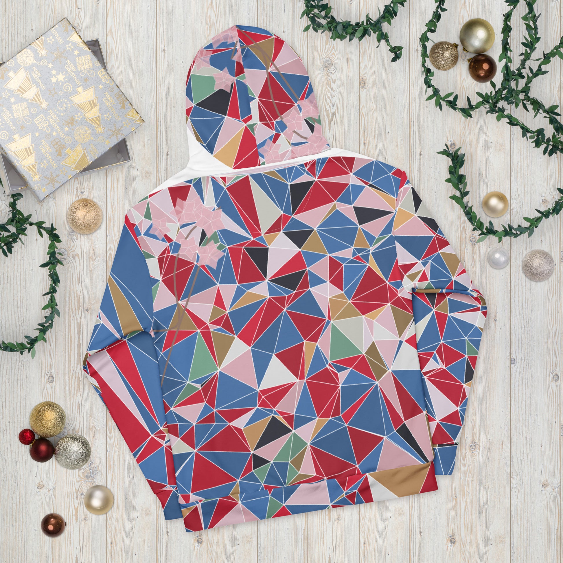 Colorful geometric-patterned jacket on a wooden surface with Christmas decorations.